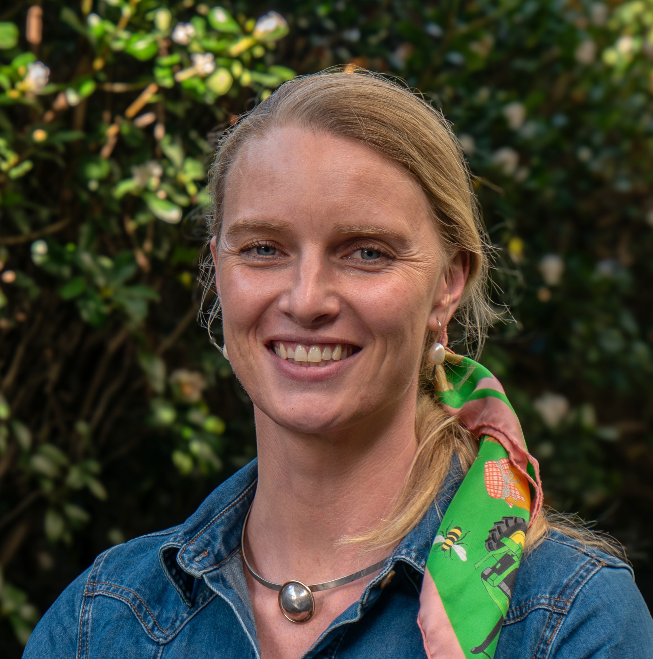 Ellie smiling with a demin shirt and a colourful hair scarf